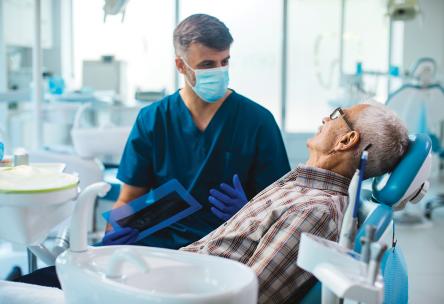 A dentist talking to a patient sitting in a dental chair