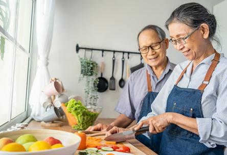 Two older people cook a meal together