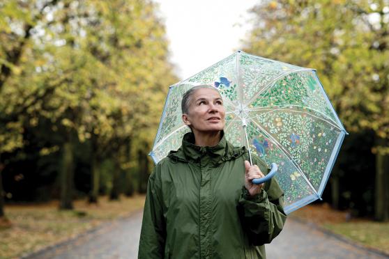 A senior woman stands outside in the rain