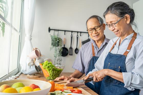 Two older people cook a meal together